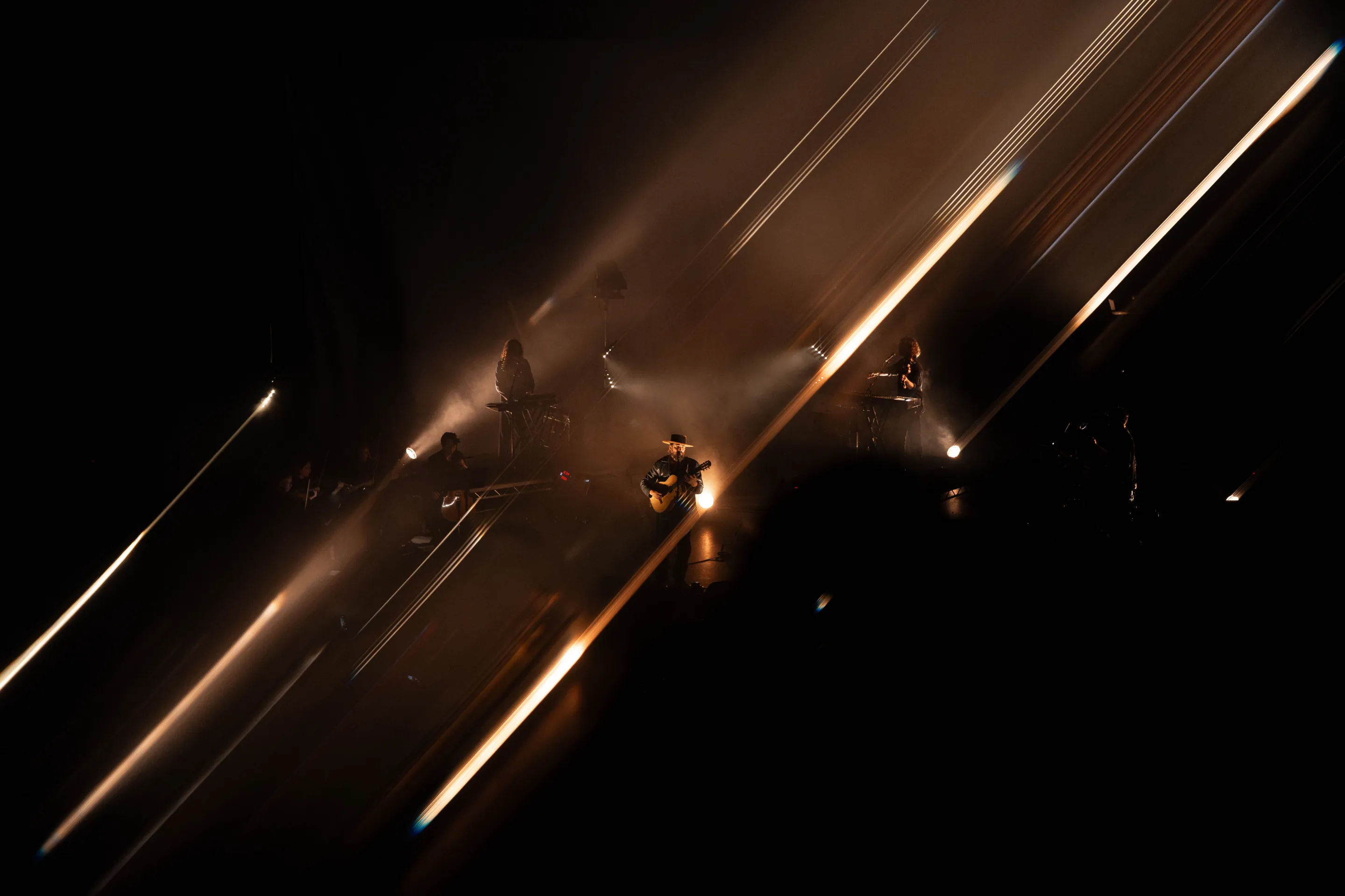 ry x, live performance, indie pop electronica artist, playing guitar with immersive lighting and visuals with audience interaction at a concert.